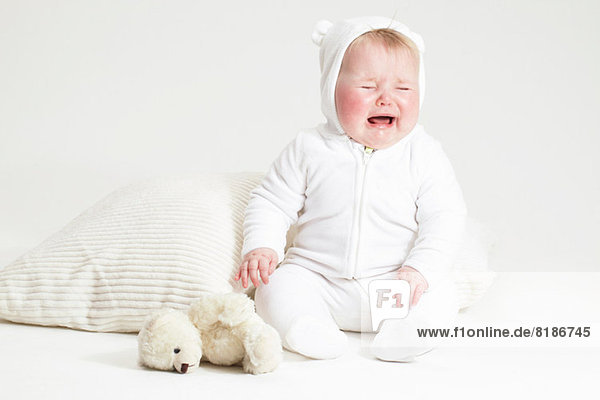 Portrait of crying baby girl and teddy bear