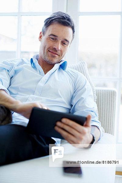 Mann auf Sofa sitzend mit digitalem Tablett