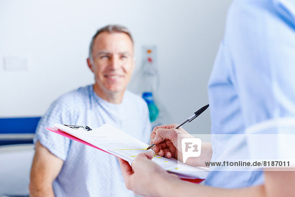 Krankenschwester beim Ausfüllen von Papierkram  Patient im Hintergrund
