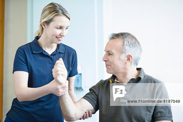 Physiotherapist helping man to do arm exercise