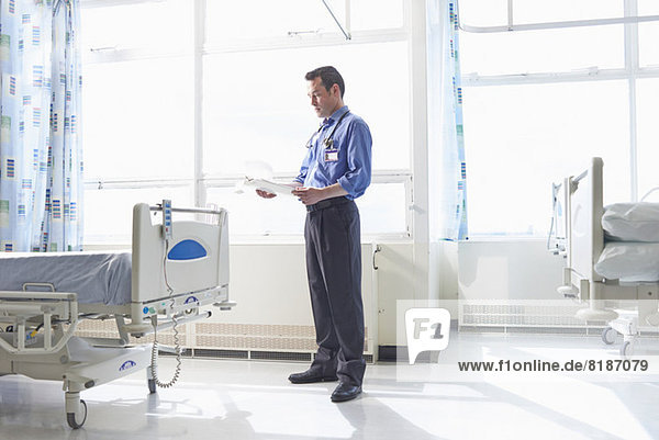 Doctor standing on hospital ward looking at medical records