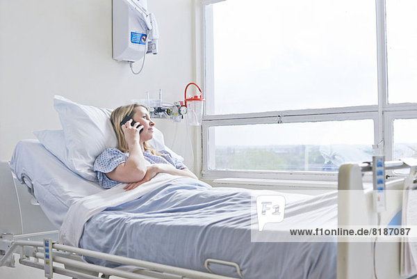 Patient lying on hospital bed on telephone call