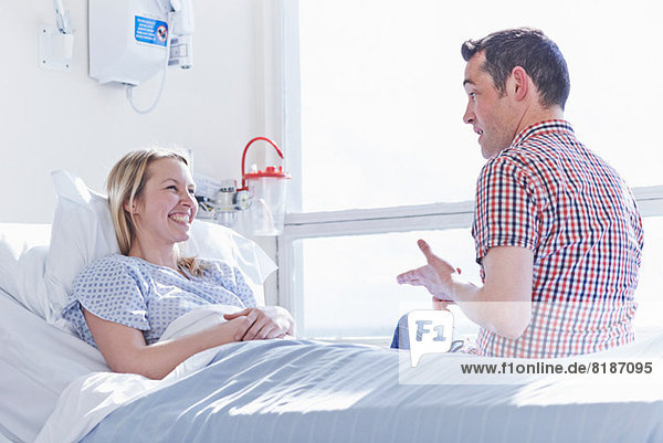 Patient liegt im Krankenhausbett und spricht mit dem Besucher