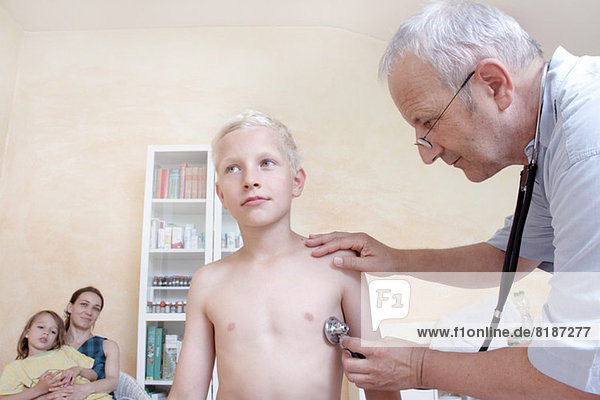 Junge wird vom Arzt mit Stethoskop untersucht