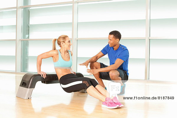 Woman doing exercise on step with man instructing