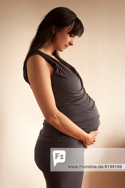 Schwangere Frau meditiert  während sie den Bauch hält.
