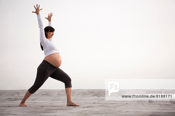 Schwangere Frau in Yoga-Kriegerpose