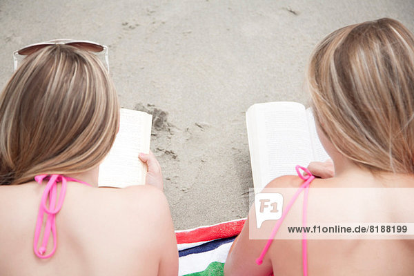 Junge Frauen beim Lesen von Büchern am Strand
