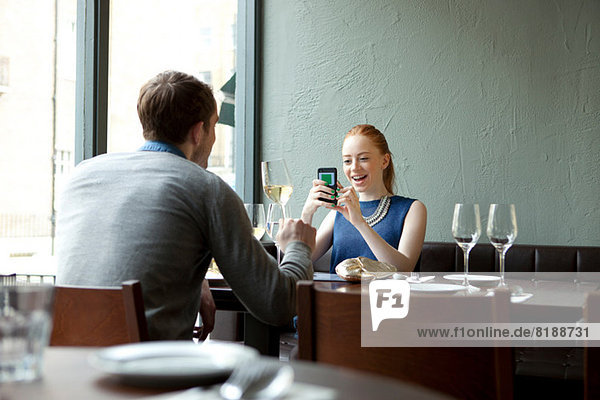 Young couple in restaurant  woman using cell phone