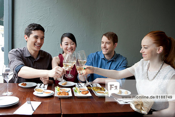 Four friends toasting white wine in restaurant