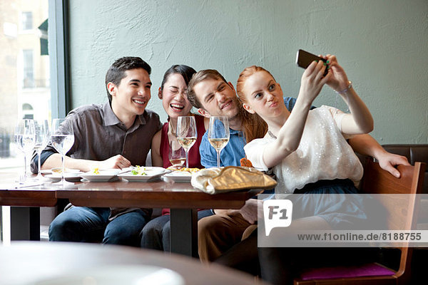 Four friends photographing themselves in restaurant
