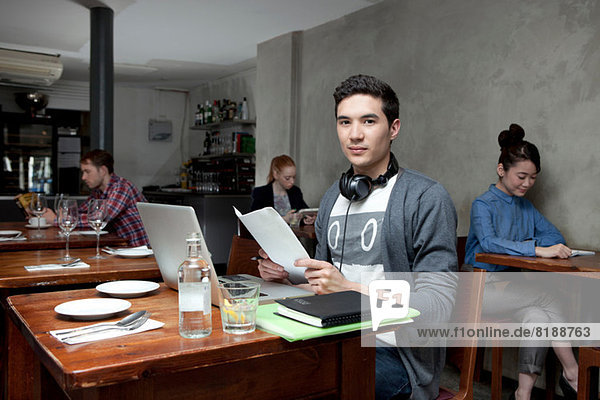 Junger Mann mit Laptop im Café