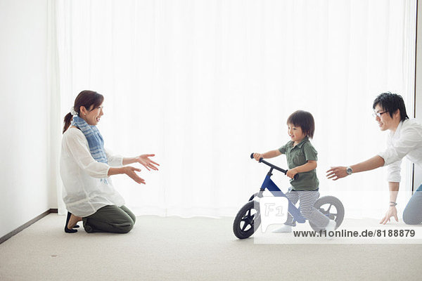 Eltern mit Sohn lernen Fahrrad fahren
