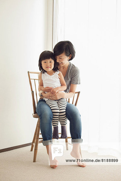 Mother and daughter sitting on wooden chair  portrait