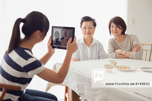 Teenage girl using tablet to photograph mother and grandmother