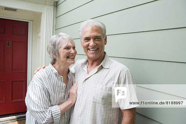 Seniorenpaar lächelt gemeinsam vor dem Haus  Porträt