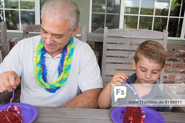 Enkel und älterer Mann essen Geburtstagstorte