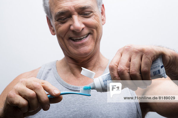 Senior Mann drückt Zahnpasta auf die Bürste