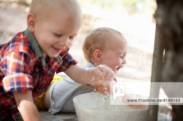 Kleinkind Zwillinge spritzen in einer Schüssel mit Wasser