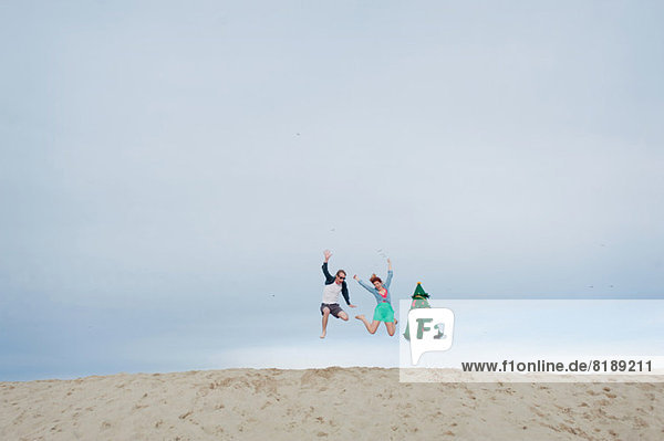Young couple leaping on beach