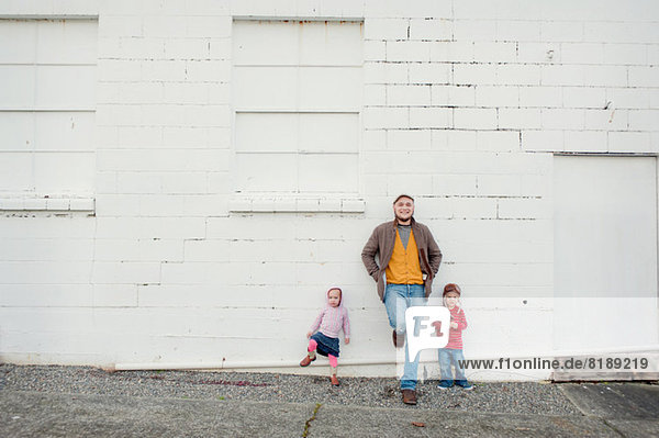 Mid adult man and son and daughter leaning against wall  portrait