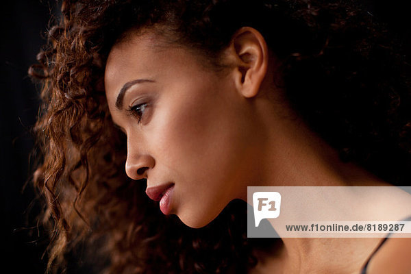 Junge Frau im Profil vor schwarzem Hintergrund