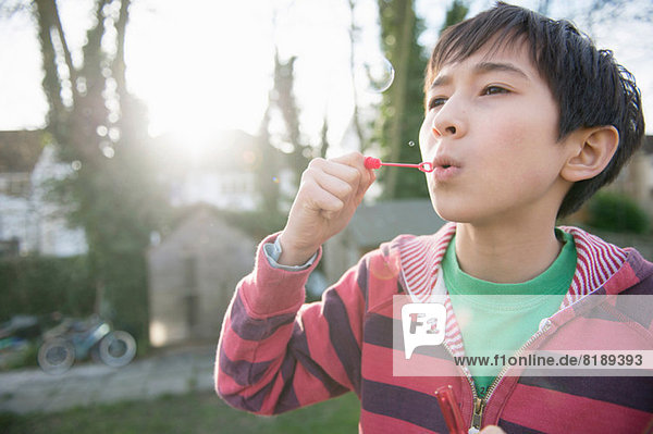 Boy blowing bubbles with wand  close up
