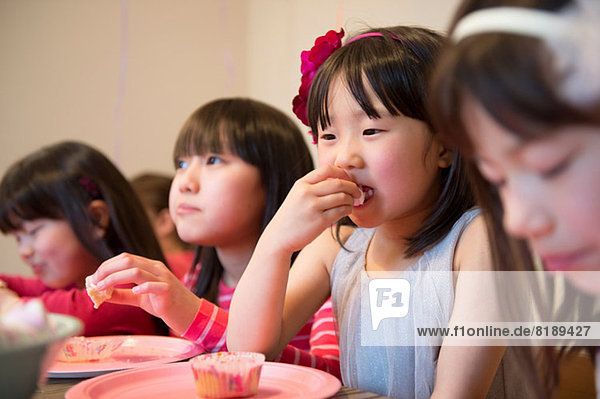 Girl's eating fairy cakes at party
