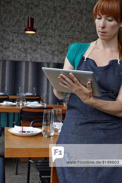 Mittlere erwachsene Frau mit digitalem Tablett im Restaurant