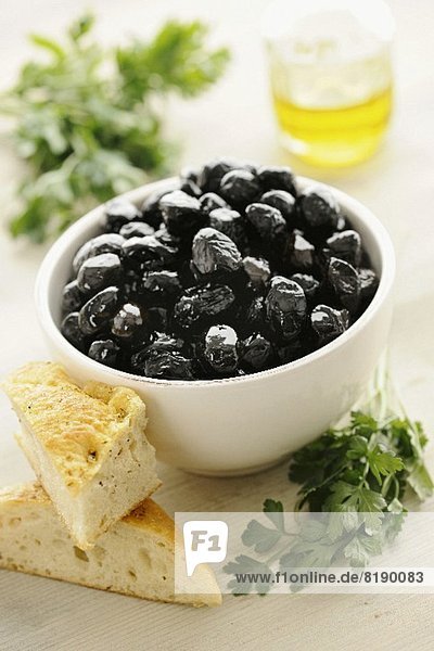 Black olives in a bowl  with bread and parsley
