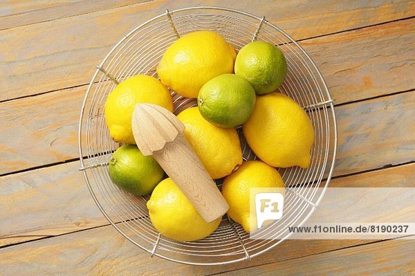 Zitronen und Limetten im Drahtkorb mit Presse