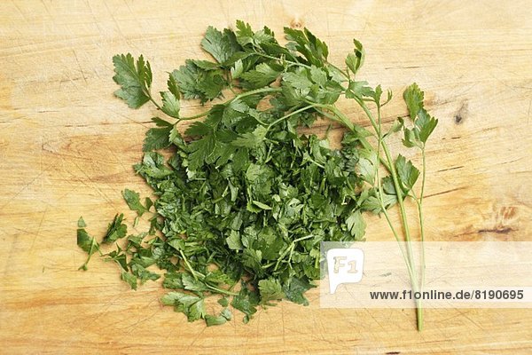 Fresh parsley  whole and chopped  on a wooden surface