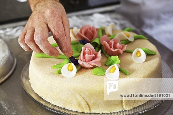 Konditor dekoriert Marzipantorte mit Marzipanblumen