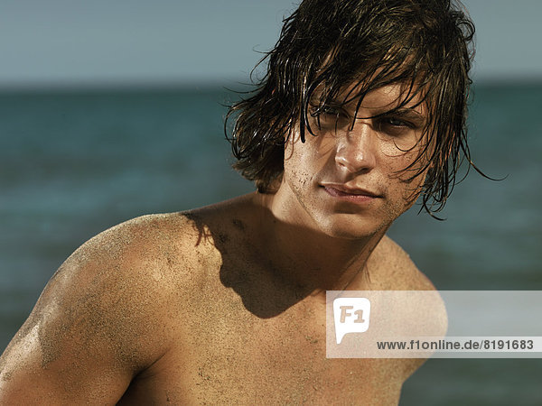 Mann mit nackter Brust und nassen Haaren am Meer