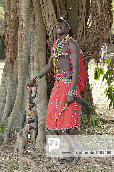 Massai-Krieger in traditioneller Kleidung und in typischer Haltung auf einem Bein