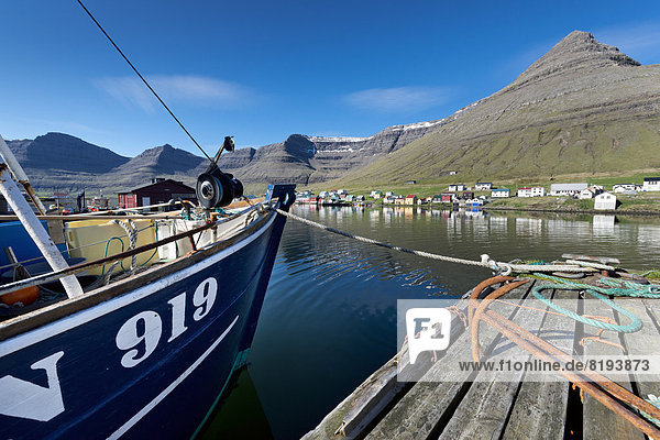 Fischerboot und rostige Anker im Hafen von Hvannasund  hinten die Ortschaft Norðdepi