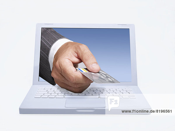 Managerhand  die eine Kreditkarte durch den Lap-Top-Bildschirm gibt  digitales Composite