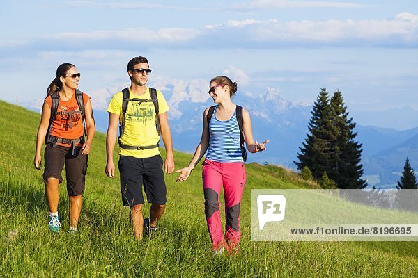 Junge Leute beim Bergwandern auf einer Almwiese in der Osterhorngruppe Salzburger Land Österreich