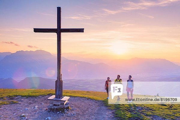 Junge Leute bei Sonnenuntergang beim Gipfelkreuz in der Osterhorngruppe Salzburger Land Österreich