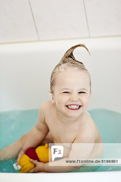 Fröhliches kleines Mädchen in der Badewanne