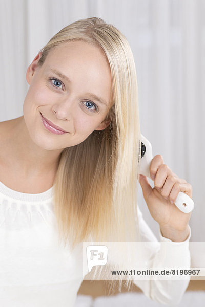 Portrait of young woman brushing her hair  smiling