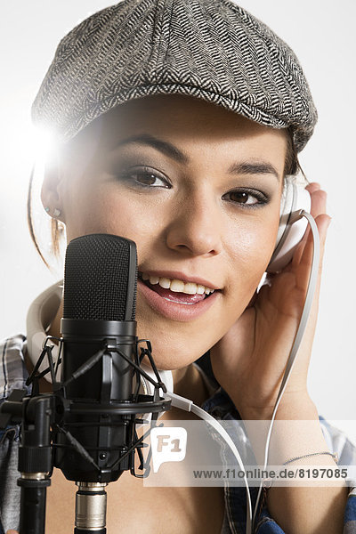 Portrait of young woman singing in microphone  smiling