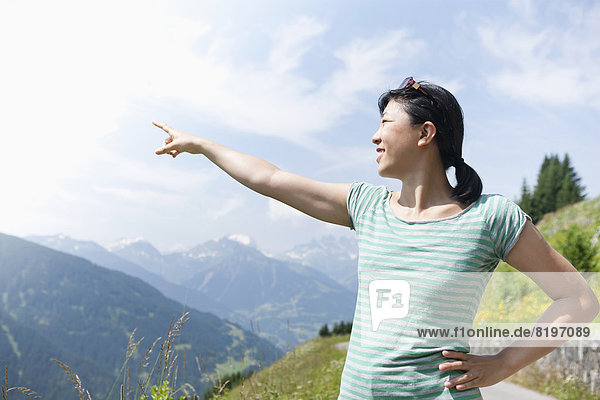 Austria  Young woman pointing at mountain hill