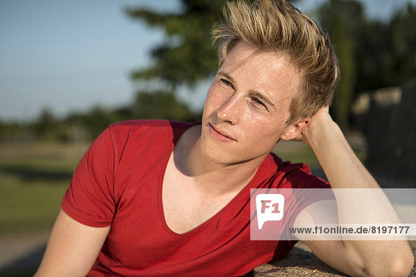 Germany  Young man sitting in park  looking away