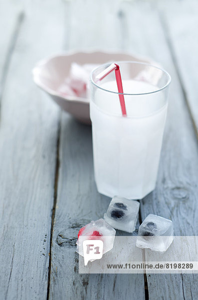 Glas Soda mit Eiswürfeln und gefrorenen Beeren auf Holztisch  Nahaufnahme