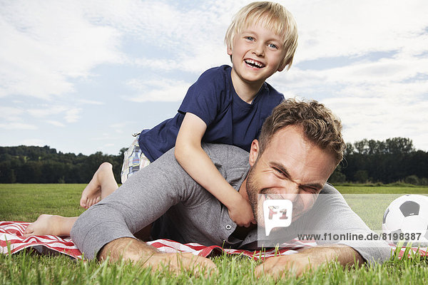 Germany  Cologne  Father and son playing around on picnic blanket