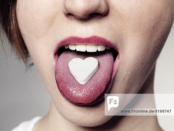 Junge Frau mit süßem Herzen auf der Zunge  Nahaufnahme  Mund