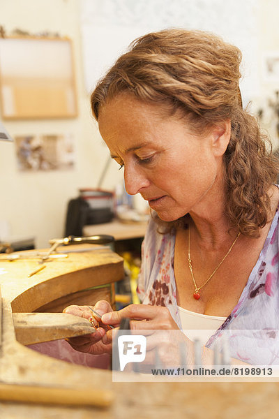 Mature woman working on ring in her workroom at home