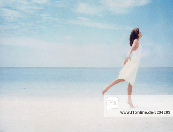 Frau am Strand  auf einem Bein balancierend