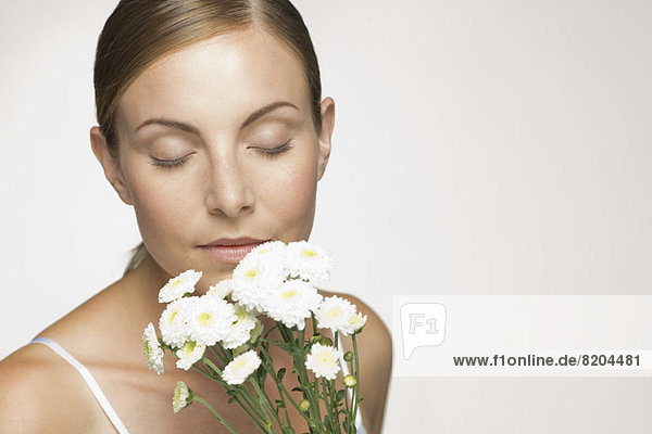 Young woman enjoying fragrence of bouquet of daisies
